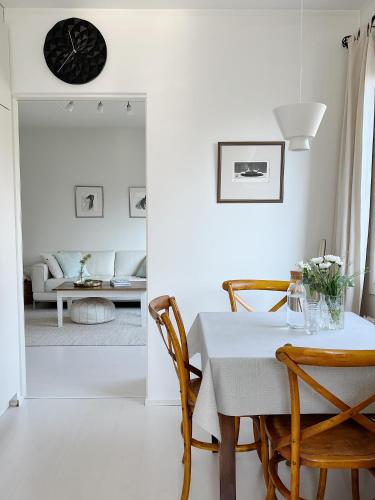 a white dining room with a table and chairs at Cozy apartment with free parking in Espoo