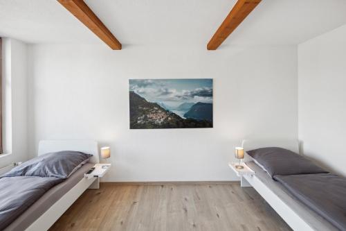 two beds in a bedroom with white walls and wood floors at FENUS Apartment mit traumhaftem Bergblick SGT02 in Grabs