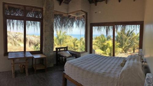 a bedroom with a bed and a view of the ocean at Marcilia Beach Bungalows in Los Órganos
