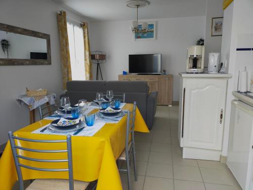 ein Esszimmer mit einem gelben Tisch und Stühlen in der Unterkunft Maison au coeur de Saint-Gilles L'Inattendue in Saint-Gilles-Croix-de-Vie