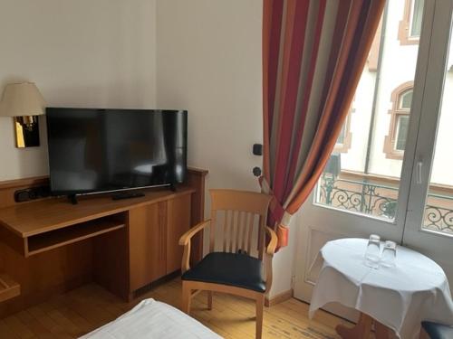 um quarto com uma televisão, uma cadeira e uma mesa em Hotel Römischer Kaiser em Trier