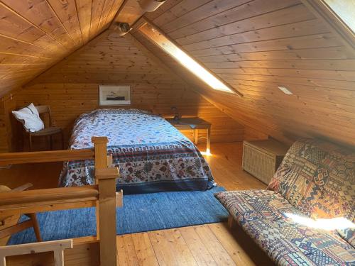 um quarto num chalé de madeira com uma cama e um sofá em Muckle Flugga em Goleen