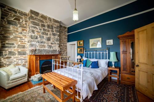 a bedroom with a bed and a stone wall at Poet's Cottage Stanley in Stanley