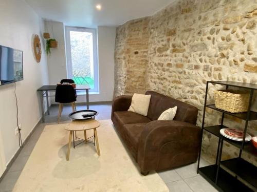 a living room with a couch and a stone wall at Vaste Appartement Rénové - Centre Ville in Bourg-en-Bresse