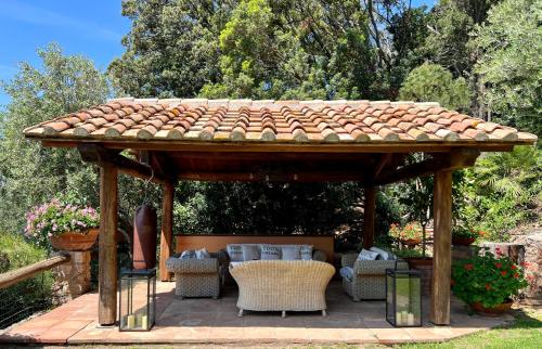 een houten prieel met een tafel en stoelen bij Villa a Cala Piccola in Monte Argentario