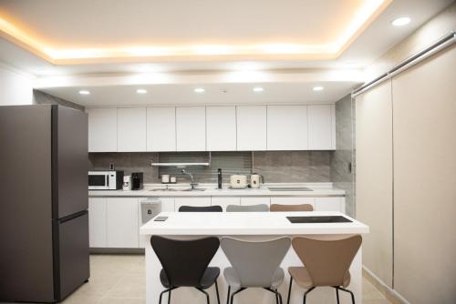 a kitchen with white cabinets and a black refrigerator at Beautipool Pension in Jeju