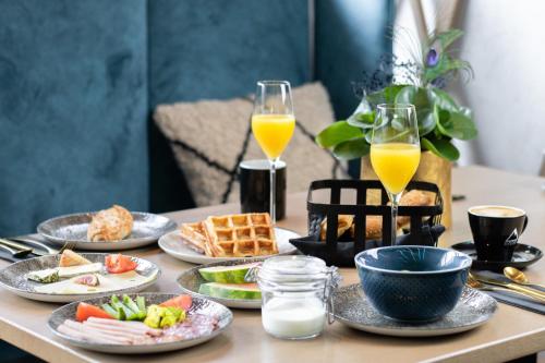 una mesa con platos de comida y dos vasos de zumo de naranja en GLEMM by AvenidA Superior Hotel & Residences en Saalbach Hinterglemm