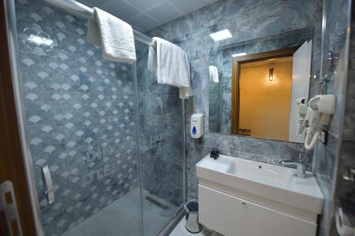 a bathroom with a shower and a sink and a mirror at MİDYAT LADİNOS OTEL in Midyat