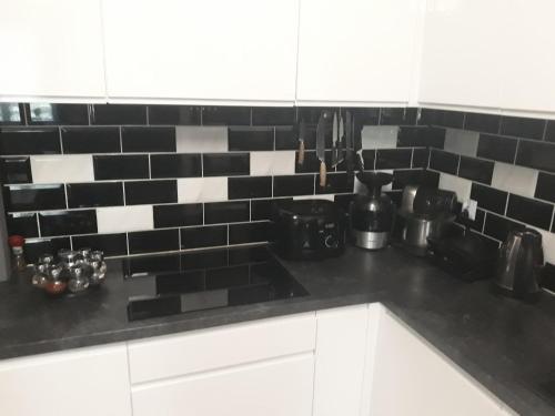 a kitchen with black and white tiles on the wall at Słoneczny Domek Mielno in Mielno