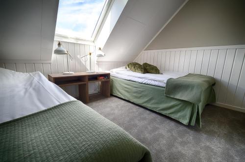 a attic room with two beds and a window at Apelviken Lägenhetshotell in Varberg