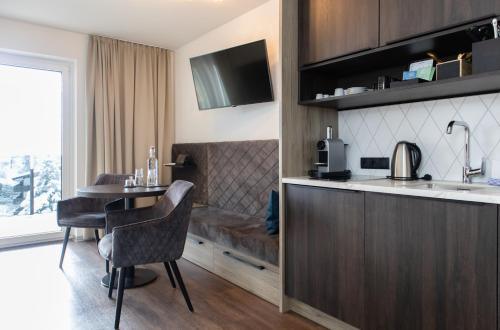 a kitchen with a table and a dining room at GLEMM by AvenidA Superior Hotel & Residences in Saalbach Hinterglemm