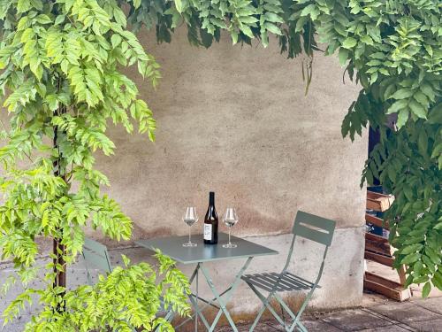 a table with a bottle of wine and two chairs at La vieille ferme de Gaillac in Gaillac