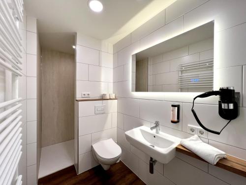 a white bathroom with a sink and a toilet at Familienhotel "Rhön Feeling" in Bernshausen