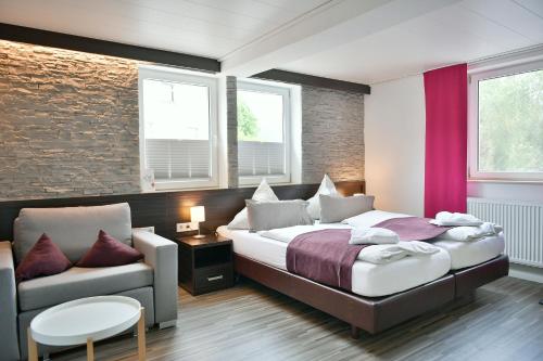 a bedroom with a bed and a couch and a chair at Familienhotel "Rhön Feeling" in Bernshausen