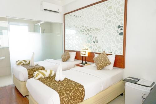 a room with two beds and a large screen at Samsara Inn in Legian