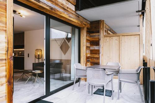 a dining room with glass doors and a table and chairs at GLEMM by AvenidA Superior Hotel & Residences in Saalbach Hinterglemm
