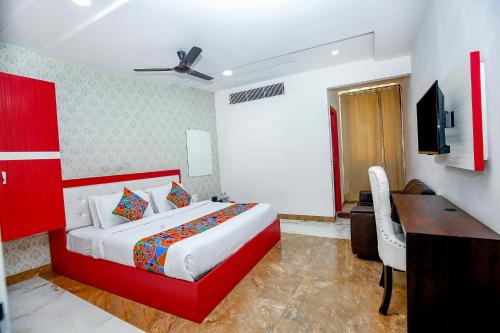 Habitación de hotel con cama roja y escritorio. en FabHotel Golden Temple Paradise, en Amritsar