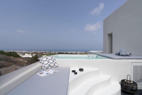 a white bathroom with a tub and a swimming pool at Maeva Suites Santorini in Pirgos