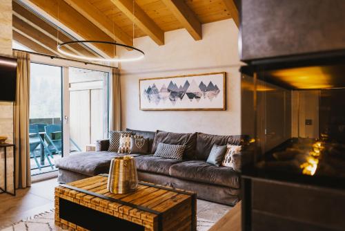 a living room with a leather couch and a table at GLEMM by AvenidA Superior Hotel & Residences in Saalbach Hinterglemm