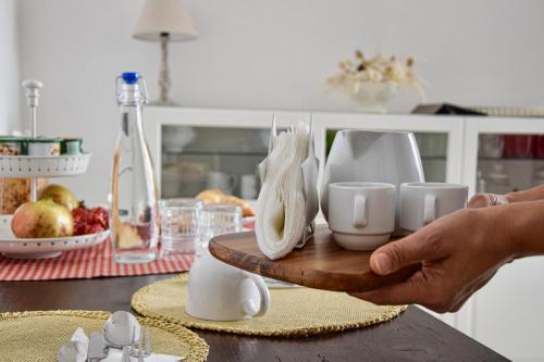 une personne tenant un plateau avec des tasses et des plats sur une table dans l'établissement La luna nel pozzo, à Botrugno