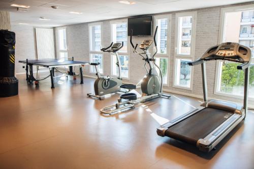 a gym with a treadmill and a table and windows at Twenty Business Flats Nîmes Trigone in Nîmes