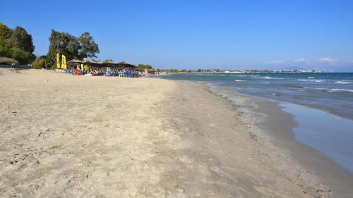 a sandy beach with a group of people on it at ZOIS APARTMENT in Artemida