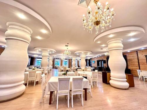 a restaurant with white tables and chairs and a chandelier at Deluxe Park Qusar Resort & Spa Hotel in Qusar