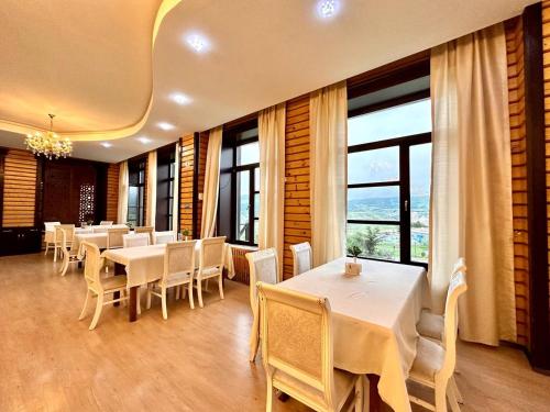 a restaurant with white tables and chairs and windows at Deluxe Park Qusar Resort & Spa Hotel in Qusar
