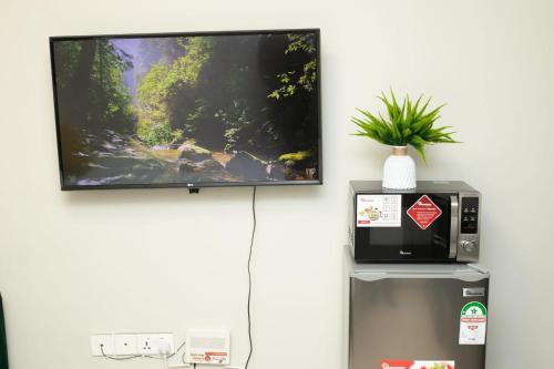 a tv hanging on a wall next to a refrigerator at Indesign Makumbi park studio Apartment D4-5,Syokimau in Syokimau