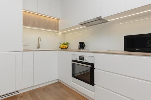 a white kitchen with white cabinets and a microwave at Cozy & Sunny Studio for 4 Guests Kolejowa Warsaw by Renters in Warsaw