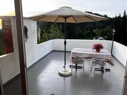 una mesa y sillas con una sombrilla en el balcón en THE MILKY WAY @ PINE RESORT, en Bukit Fraser