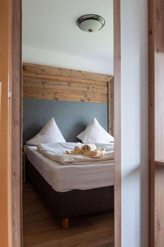 a bed with a wooden headboard and white pillows at Ferienwohnung Grundlsee - Your Austrian Home in Grundlsee