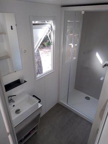 une salle de bain blanche avec un lavabo et une douche dans l'établissement Joli 2 chambres sur Lumio, vue à couper le souffle., à Lumio