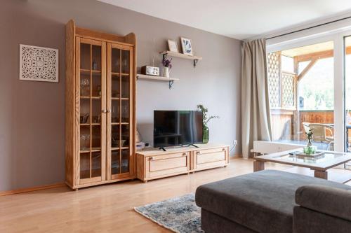 a living room with a television and a wooden cabinet at Ferienwohnung Grundlsee - Your Austrian Home in Grundlsee