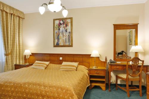 a bedroom with a bed and a desk and a mirror at Hotel Kolonada in Karlovy Vary