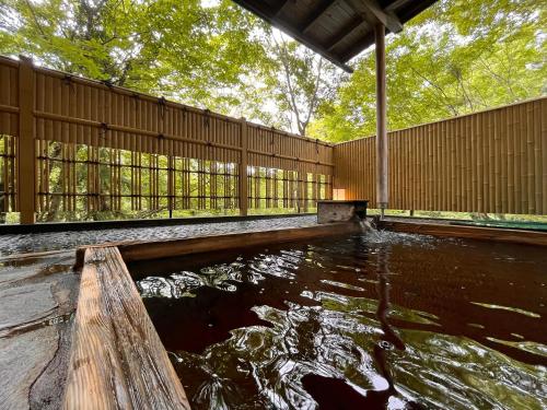 einen Teich mit einem Holzzaun in der Unterkunft 丸山鉱泉旅館 