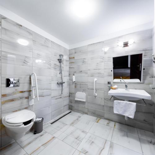 a white bathroom with a toilet and a sink at Hotel Vécsecity in Hernádvécse