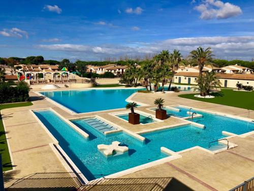 una grande piscina blu con sedie e palme di Domaine Les Tamaris - Portes du Soleil - Villa 3 chambres avec Jardin - Climatisation - Accès Animations et Piscines inclus ! a Portiragnes