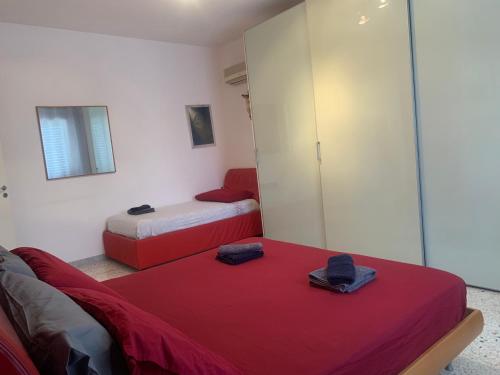 Habitación con 2 camas con sábanas rojas y espejo. en Casa vacanza Ilaria, en Torre Lapillo