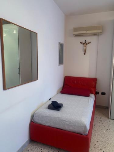 1 dormitorio con cama roja y espejo en Casa vacanza Ilaria, en Torre Lapillo