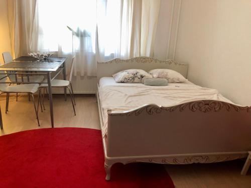 a bedroom with a bed with a table and a red rug at Sweet home 40 City Center Punavuori in Helsinki