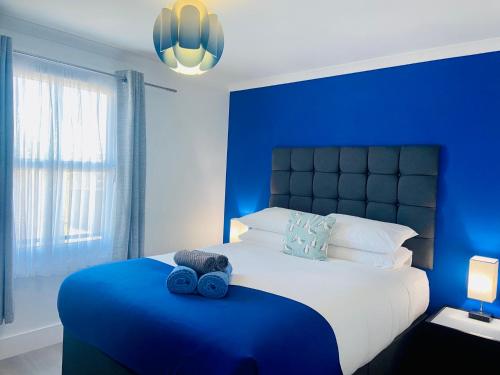 a blue bedroom with a bed with a blue headboard at Oceano - Carbis bay, St Ives, 1 bed apartment with free parking near to the beach in St Ives