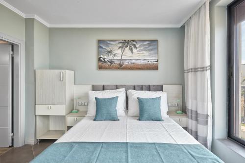 a bedroom with a large white bed with blue pillows at 3BD Beach Paradise with a Stunning View with Parking by Flat Mаnаger in Nesebar