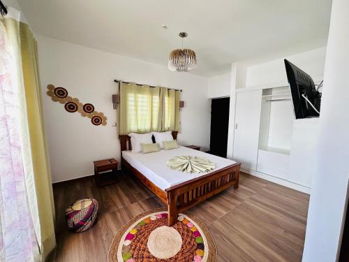 a bedroom with a bed and a television in it at Ofim Holidays in Ambohidratrimo