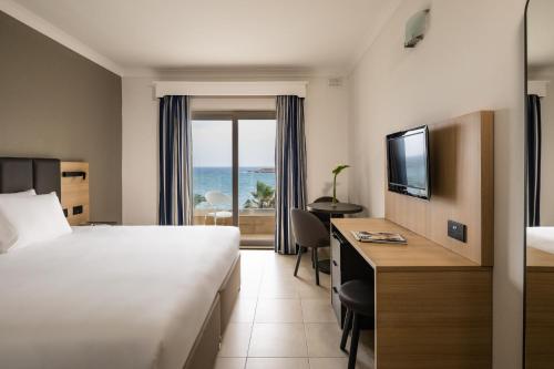 a hotel room with a bed and a view of the ocean at QAWRA Palace Resort & SPA in St. Paul's Bay