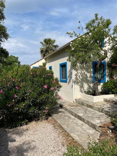 a white house with blue windows and some bushes at Quinta Inge in Paio Mendes