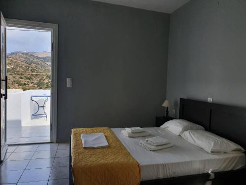a bedroom with a bed with a table and a balcony at Galini Rooms Sikinos Travel in Síkinos