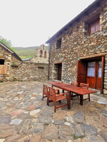 a wooden picnic table in front of a stone building at Casa Rural con patio y BBQ en La Vall de Boí in Cardet