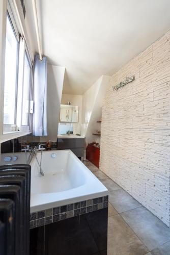 une grande baignoire blanche dans une salle de bain avec une fenêtre dans l'établissement Colonnade, à Paris