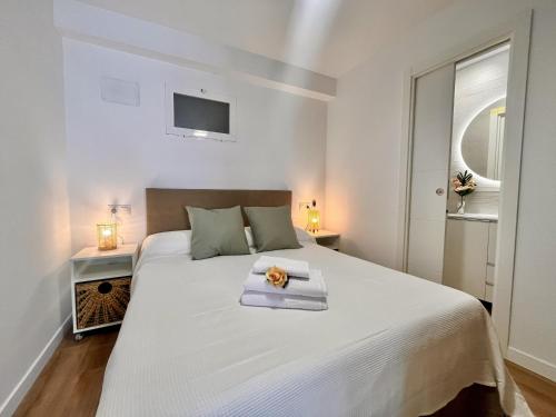 Dormitorio blanco con cama blanca grande y servilleta en Luxe Beach Three By Gloove, en Villajoyosa